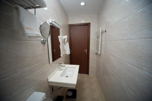 uma casa de banho com um lavatório, um espelho e um WC. em Iberia Didube em Tbilisi