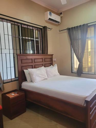 a bedroom with a large bed and two windows at KimyaKimya Pub & Lodge in Dar es Salaam