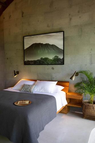a bedroom with a bed with a picture on the wall at Sejati Boutique Hotel Uluwatu in Uluwatu