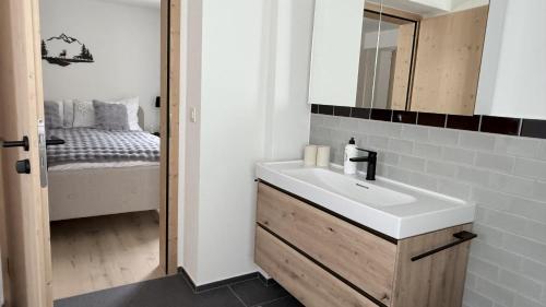a bathroom with a sink and a mirror and a bed at 5 room apartment for 8 people at Bergcafe Aurora Lenzerheide in Lenzerheide