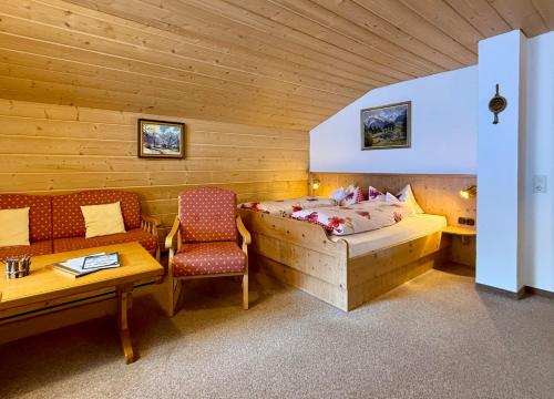 a bedroom with a bed and a table and a chair at Landhaus Spielmannsau in Oberstdorf