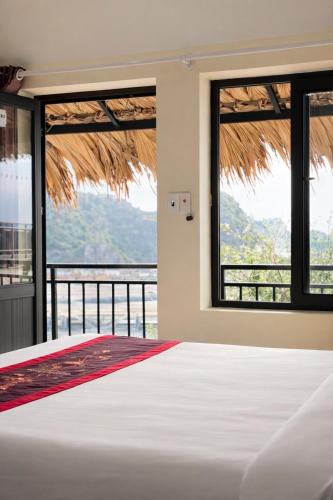 a bedroom with a bed with a view of the ocean at LePont Cat Ba Bungalow in Cat Ba