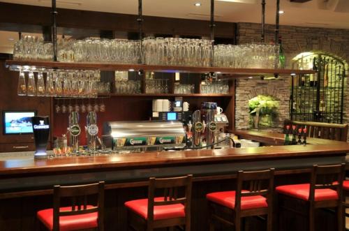 a bar with red chairs and wine glasses at Landhotel Berger in Eben im Pongau