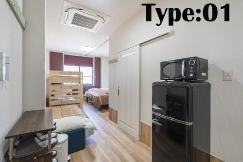 a small room with a refrigerator and a bedroom at HOTEL 萃 the 3rd-雑餉隈駅前-無人ホテル-HOTEL SUI the third-ZASSHO-Unmanned Hotel in Fukuoka