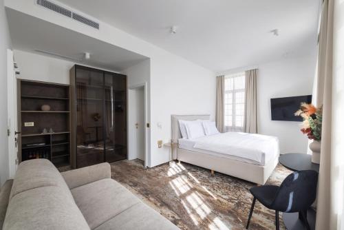 a white bedroom with a bed and a couch at Hiša F5 in Ljubljana