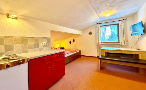a large kitchen with red cabinets and a window at Landhaus Spielmannsau in Oberstdorf