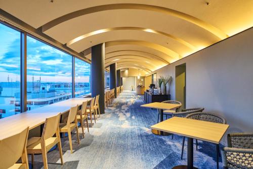 a row of tables and chairs in a room with windows at Hotel Global View Urawa in Saitama