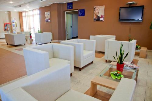 a waiting room with white chairs and a flat screen tv at Tulip Inn Turin South in Moncalieri
