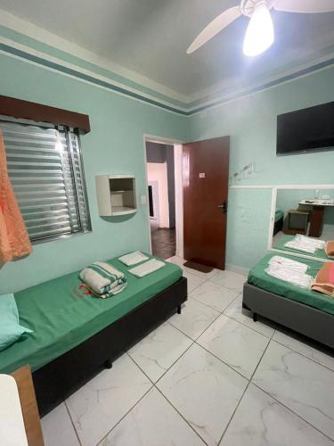a bedroom with two beds and a television in it at Hotel Karisma II in São Bernardo do Campo