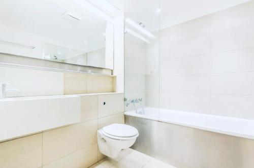 a white bathroom with a toilet and a sink at Canary Wharf Riverside gateway in London