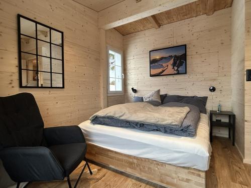 a bedroom with a bed and a chair in it at Chalet Waldhüsli - CharmingStay in Quarten