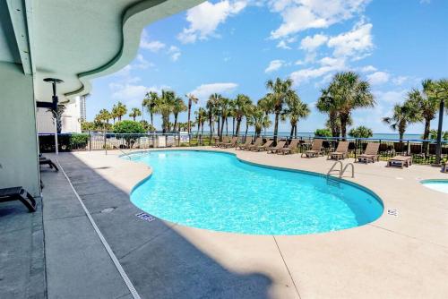 a swimming pool with chairs and the ocean in the background at Spacious Beach Condo Double Suite for Couples Getaway in Myrtle Beach