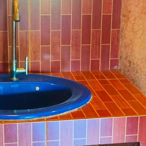 a bathroom with a blue sink on a tiled floor at Akha Hill House in Ban Doi Hang