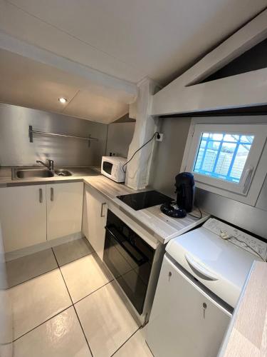 a small kitchen with white cabinets and a sink at Maisonnette chaleureuse, paisible & proche tram in Blanquefort