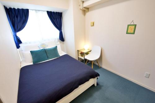 a bedroom with a bed and a window and a chair at はなハウス 401 in Ginowan