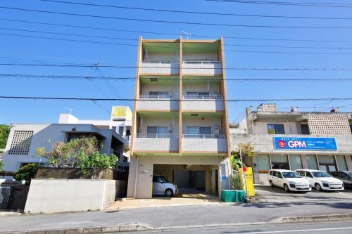 a tall building with cars parked in a parking lot at はなハウス 401 in Ginowan