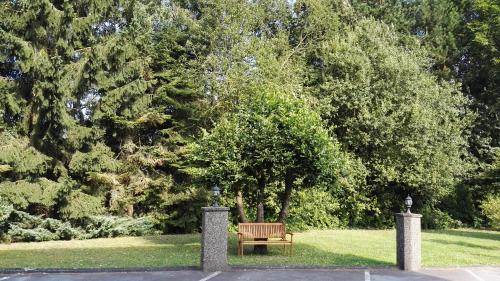 a park with a wooden bench in the grass at BIVIUS Hotel Restaurant Luxembourg in Luxembourg
