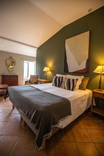 a bedroom with a large bed with green walls at Hôtel de Mirmande in Mirmande