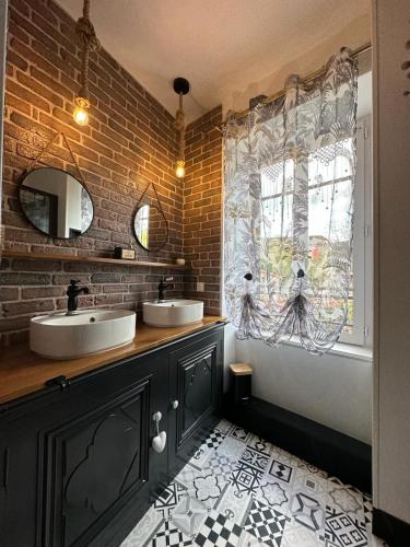 a bathroom with two sinks and a brick wall at Le clos fleuri in Saint-Gervazy