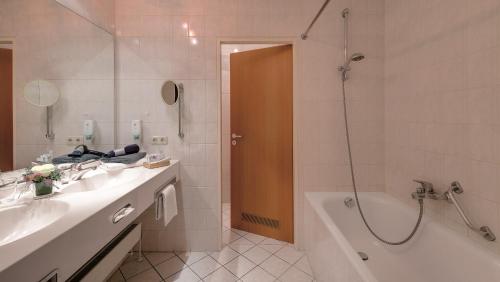 ein Bad mit einer Badewanne, einem Waschbecken und einer Dusche in der Unterkunft Best Western Aparthotel Birnbachhöhe in Bad Birnbach