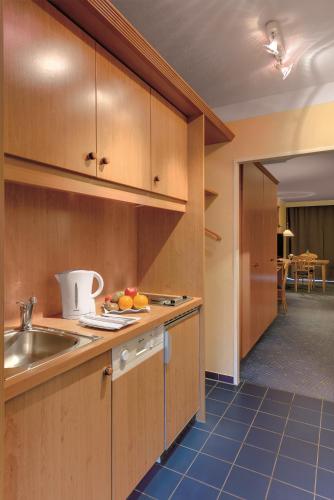 a kitchen with wooden cabinets and a sink at Best Western Aparthotel Birnbachhöhe in Bad Birnbach