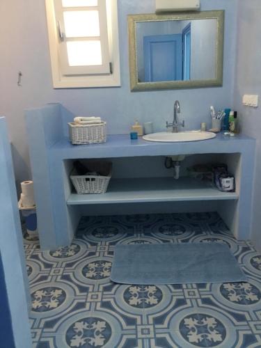 a blue bathroom with a sink and a mirror at casa koklakura in Leipsoi