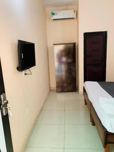 a room with a bed and a tv on the wall at Hotel Mahadev Home-Stay !! Near Chandigarh It'l Airport in Chandigarh Airport