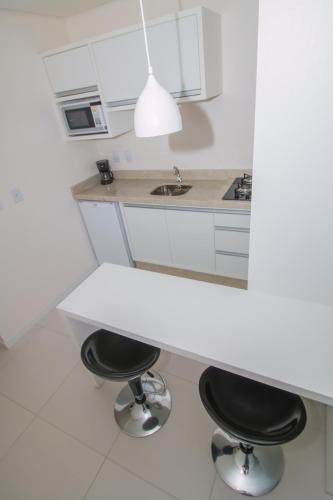 a kitchen with two bar stools and a white counter at Stúdios Ponta dos Molhes in Torres