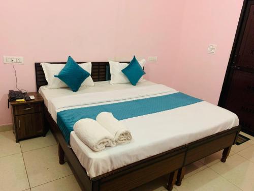 a bed with blue and white pillows and towels on it at Hotel Mahadev Home-Stay !! Near Chandigarh It'l Airport in Chandigarh Airport