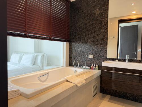 a bathroom with a large tub and a bed at The 211 Rayong in Ban Phlong Sawai