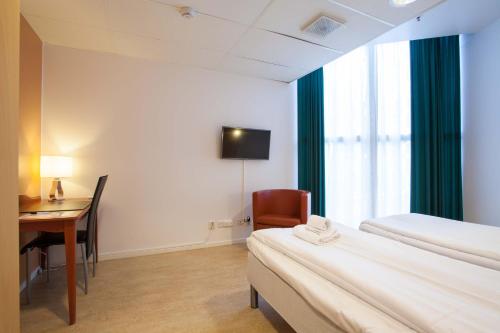 a hotel room with a desk and a bed and a chair at Pronova Hotell & Vandrarhem in Norrköping