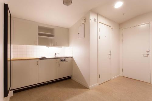 an empty kitchen with white cabinets and a sink at Pronova Hotell & Vandrarhem in Norrköping