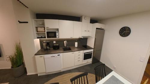a kitchen with white cabinets and a clock on the wall at Keskuskarintie 9 A3 in Kalajoki