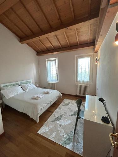 a bedroom with a bed and a table and two windows at CasaVolta in Padova