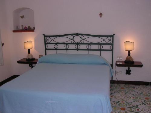 a bedroom with a bed with blue sheets and two lamps at Villa Brigio in Forio d'Ischia