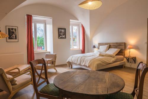 a bedroom with a bed and a table and chairs at le clos de la monne in Saint-Amant-Tallende