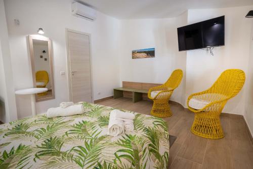 a bedroom with a bed and two chairs and a television at VILLA SEA VIEW IN SICILY, Real Relax in Fontane Bianche