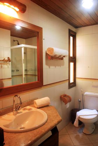 a bathroom with a sink and a mirror and a toilet at Pousada Coisa e Tao in Arraial d'Ajuda