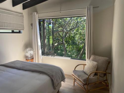 a bedroom with a bed and a chair and a window at SealPoint Studio in Cape St Francis