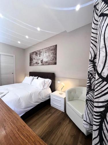 a bedroom with a large white bed and a chair at Rifugio AL in Randazzo