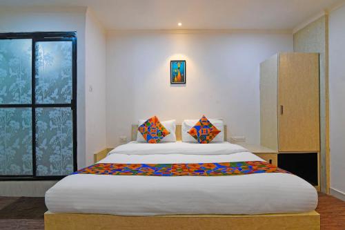 a bedroom with a large white bed with colorful pillows at FabHotel Demattrie Budget in Kolkata