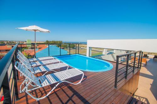 a deck with chairs and a swimming pool on a cruise ship at Ponta dos Molhes Beach Flat in Torres