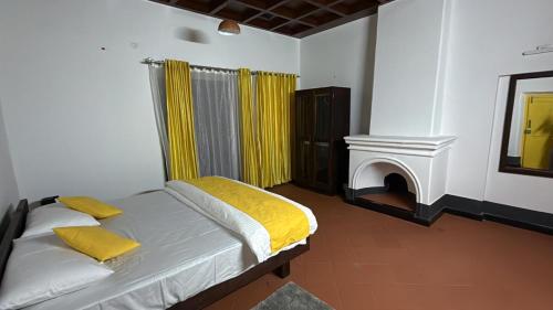 a bedroom with a bed with yellow sheets and a fireplace at Colonial canopy in Suntikoppa