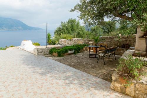 a patio with a table and chairs next to the water at Olympia House in Vathi