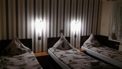 two beds in a room with two lights on the wall at Gościniec pod Różą in Chełmno