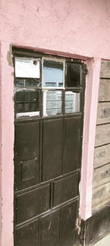 a black door in a pink wall with a window at Yua Residence in Machakos