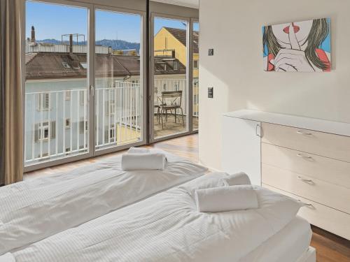 a white bed in a room with a large window at Comfortable 1BR flat at great location - Baron 44 in Zurich