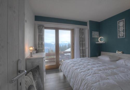 a bedroom with a large bed and a large window at Antares 402 au centre a Anzere in Anzère