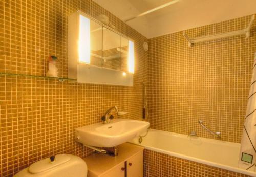 a yellow tiled bathroom with a sink and a toilet at Antares 403 au centre a Anzere in Anzère