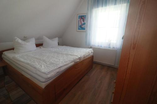 ein Schlafzimmer mit einem Bett mit weißer Bettwäsche und einem Fenster in der Unterkunft FW Lehmann in Zingst